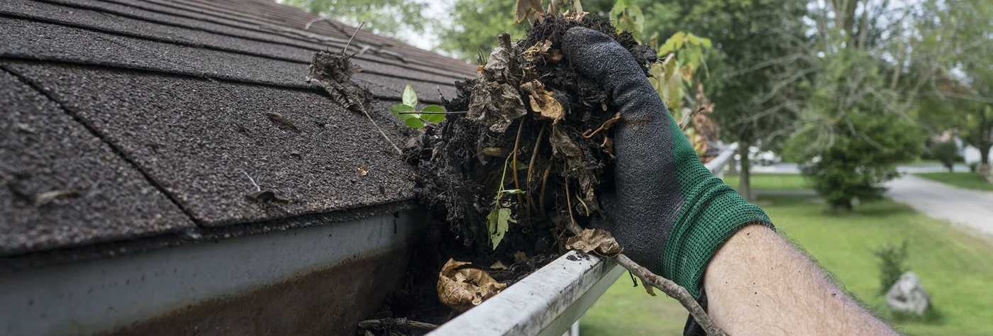 Gloved hand clearing a gutter