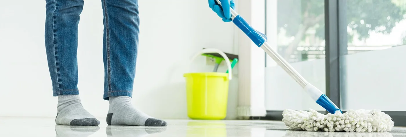Cleaner mopping a floor beside a bucket