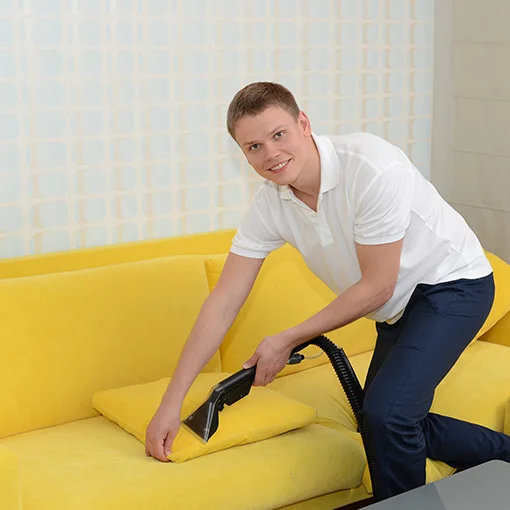 Cleaner vacuuming a sofa