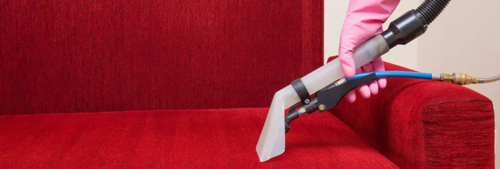 Extraction nozzle cleaning a red sofa