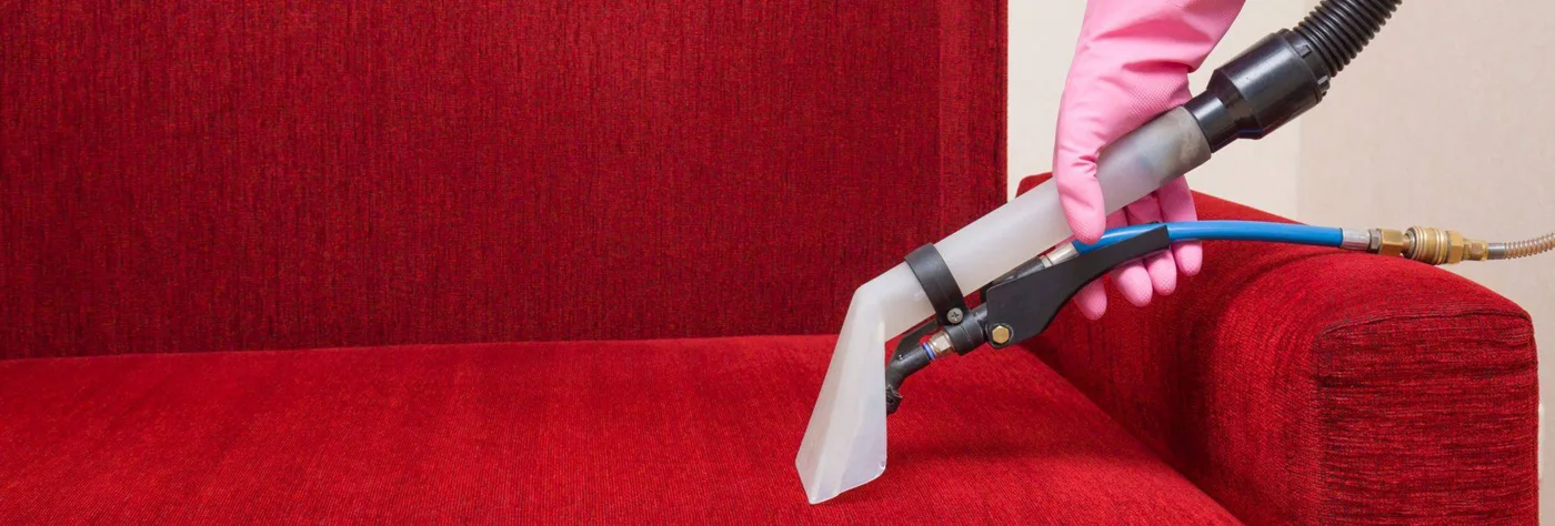 Extraction nozzle cleaning a red sofa