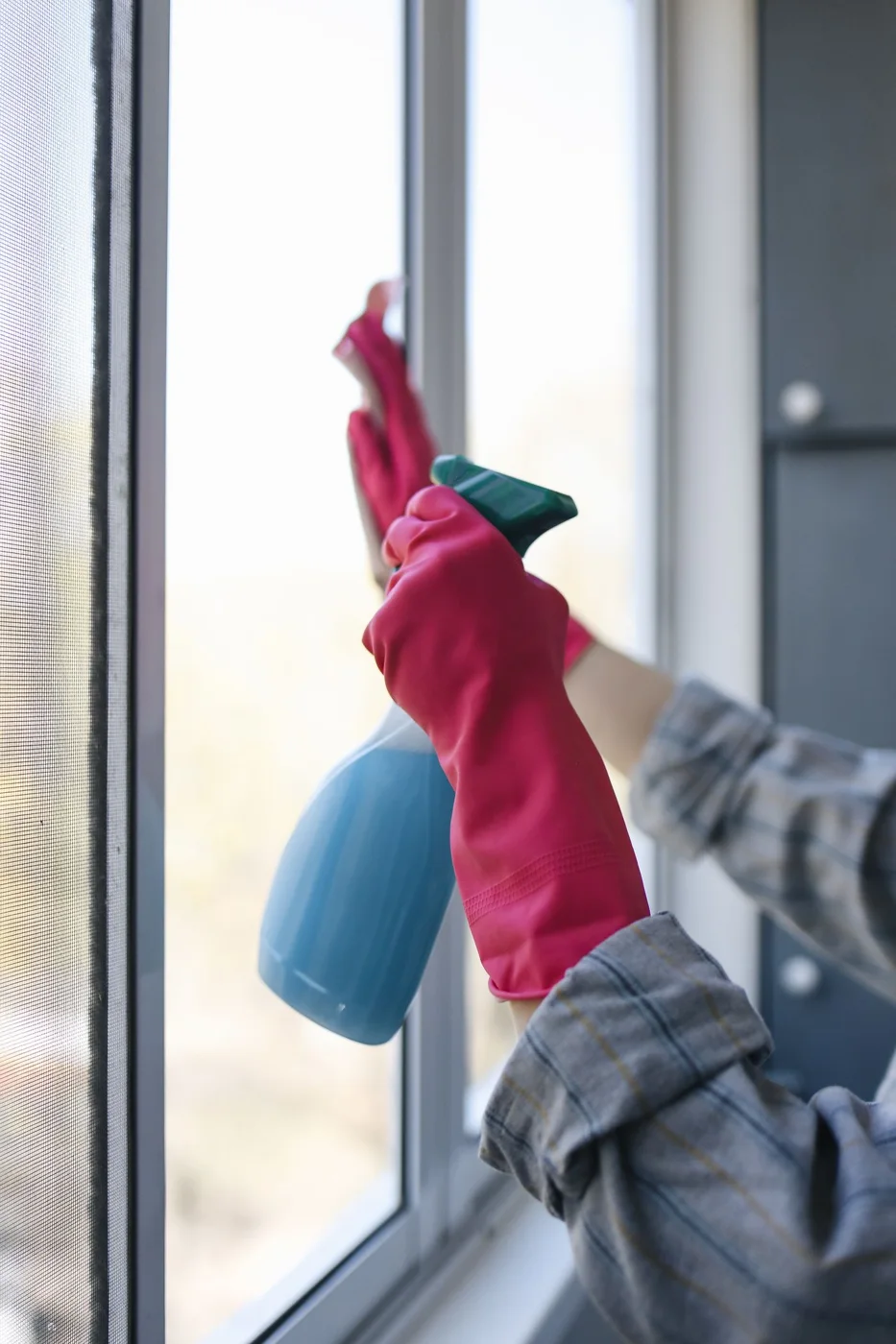 Gloved hands cleaning a glass window