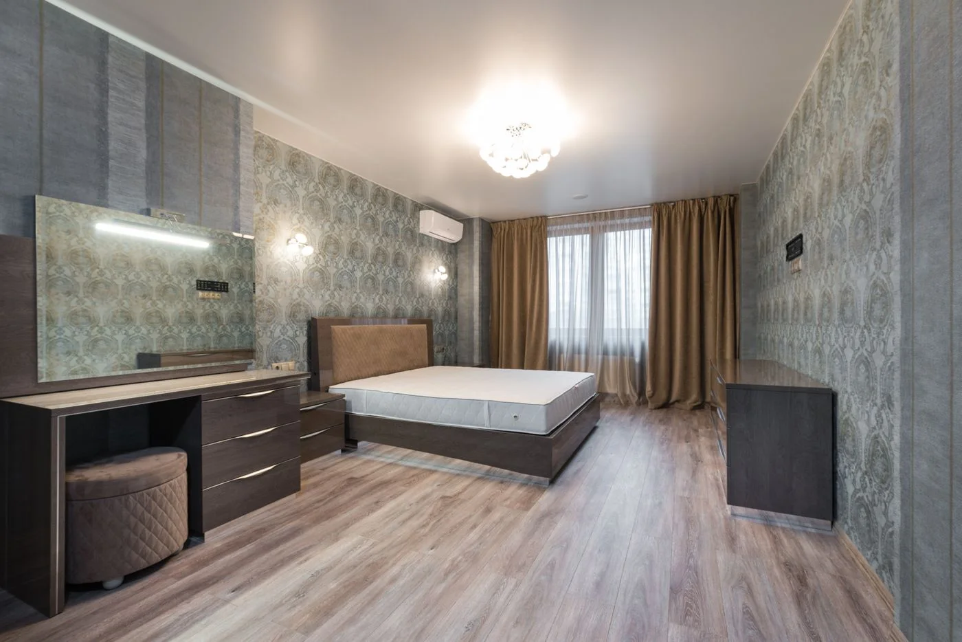 Bed with an uncovered mattress beside a window